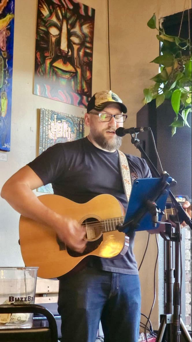 Jeremy Ross singing and playing acoustic guitar at a local venue.